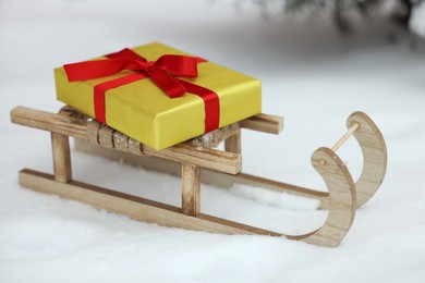 Wooden sleigh with gift box on snow outdoors