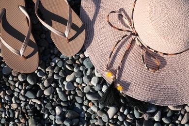 Beautiful hat with flip flops on pebbles, flat lay