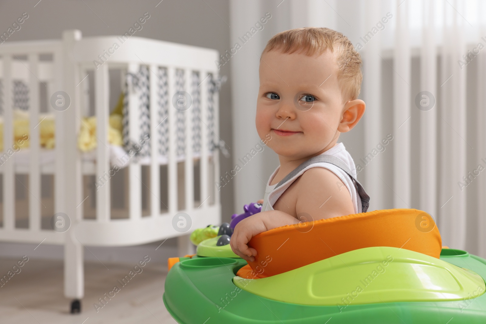 Photo of Portrait of cute baby with toy walker at home, space for text. Learning to walk