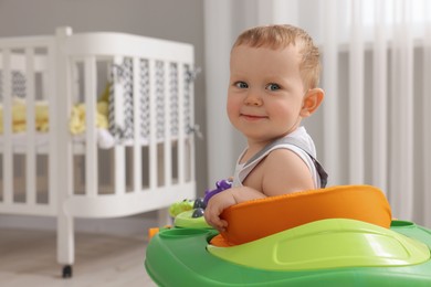 Portrait of cute baby with toy walker at home, space for text. Learning to walk