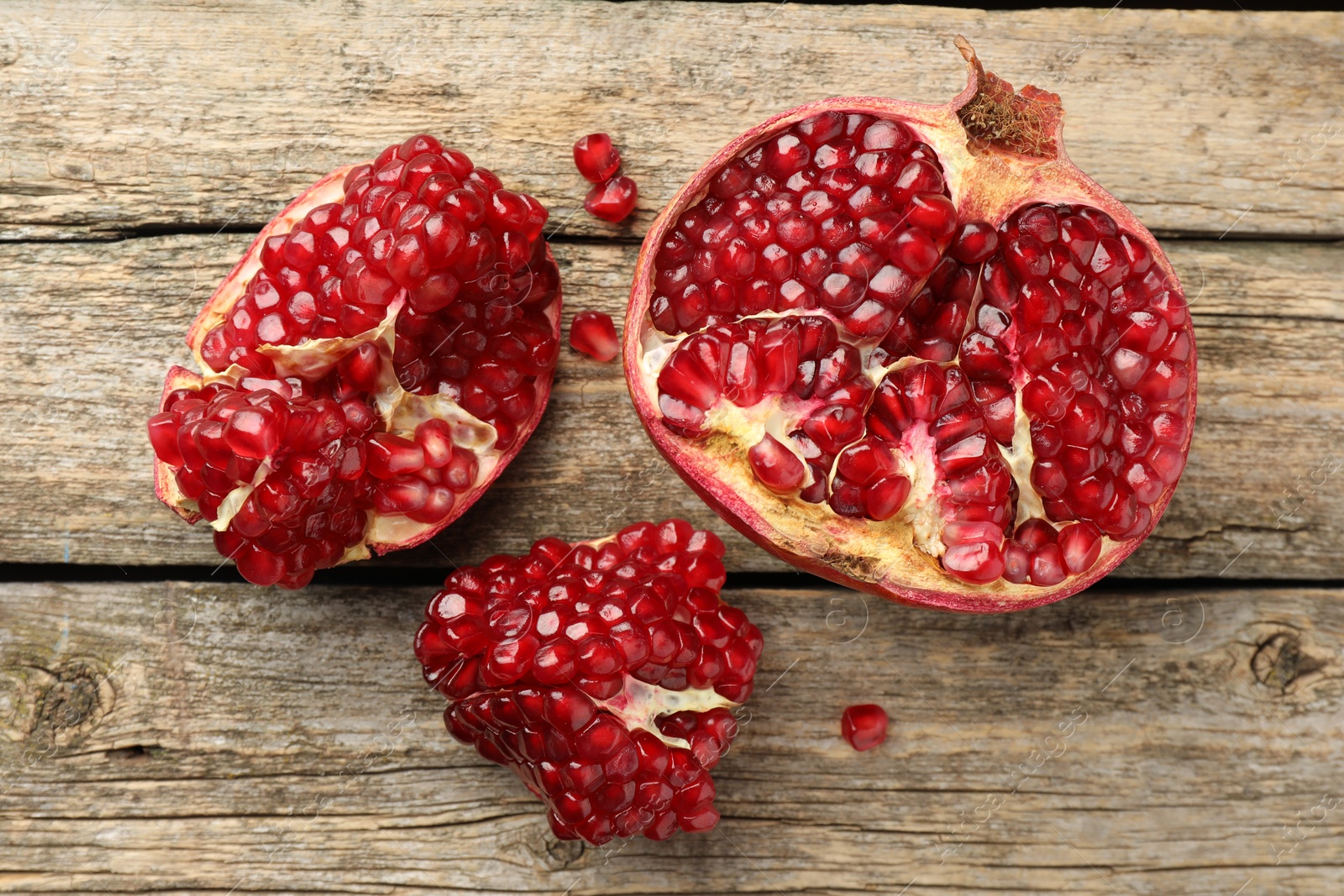 Photo of Cut fresh pomegranate on wooden table, top view