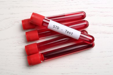 Photo of Tubes with blood samples on white wooden table, flat lay. STD test