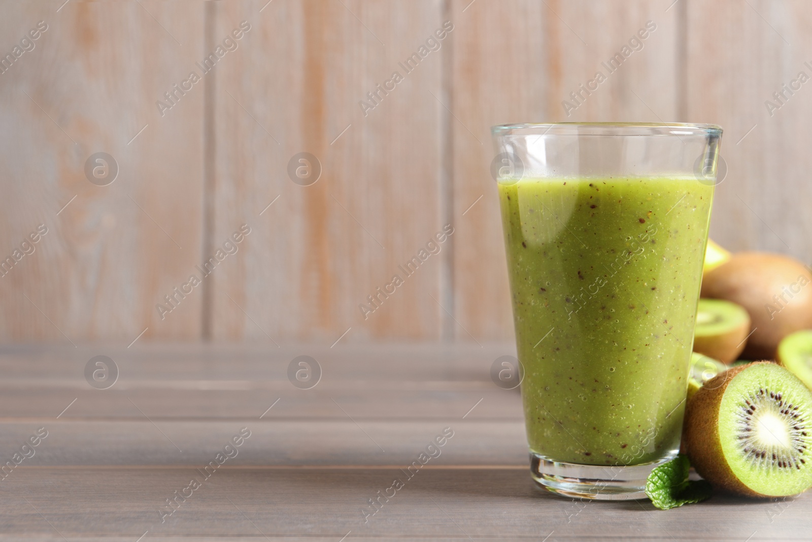 Photo of Delicious kiwi smoothie and fresh fruits on wooden table. Space for text