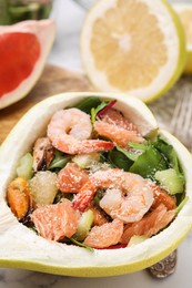 Delicious pomelo salad with shrimps in half of fruit on table, closeup