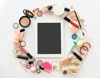 Flat lay composition with makeup products for woman and tablet on light background