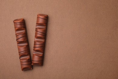 Photo of Tasty chocolate bars on brown background, flat lay. Space for text