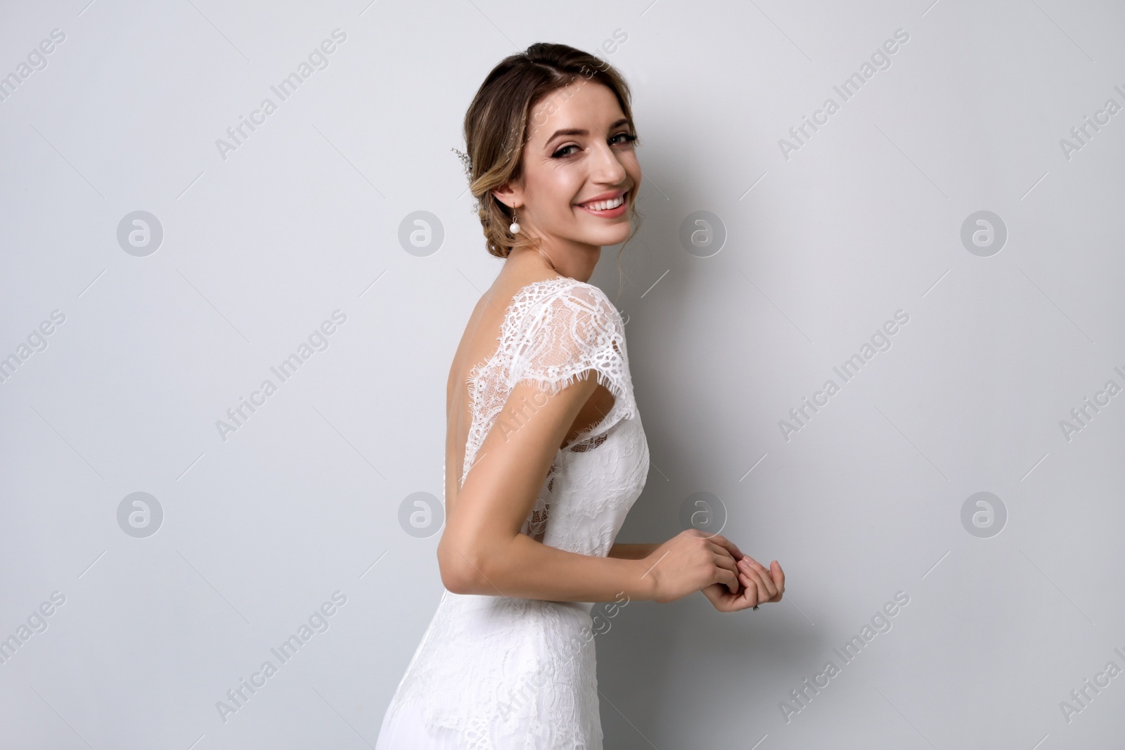 Photo of Young bride with elegant wedding hairstyle on light grey background