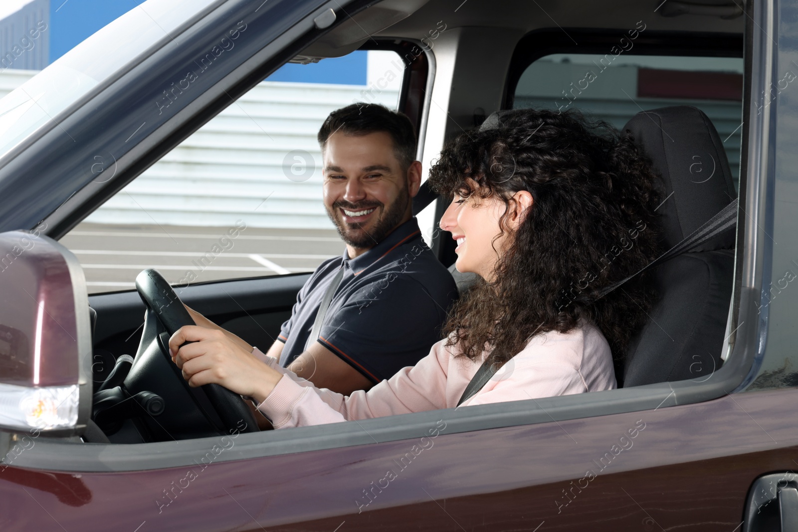 Photo of Driving school. Happy student during lesson with driving instructor in car