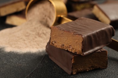 Photo of Tasty energy bar and protein powder on grey table, closeup