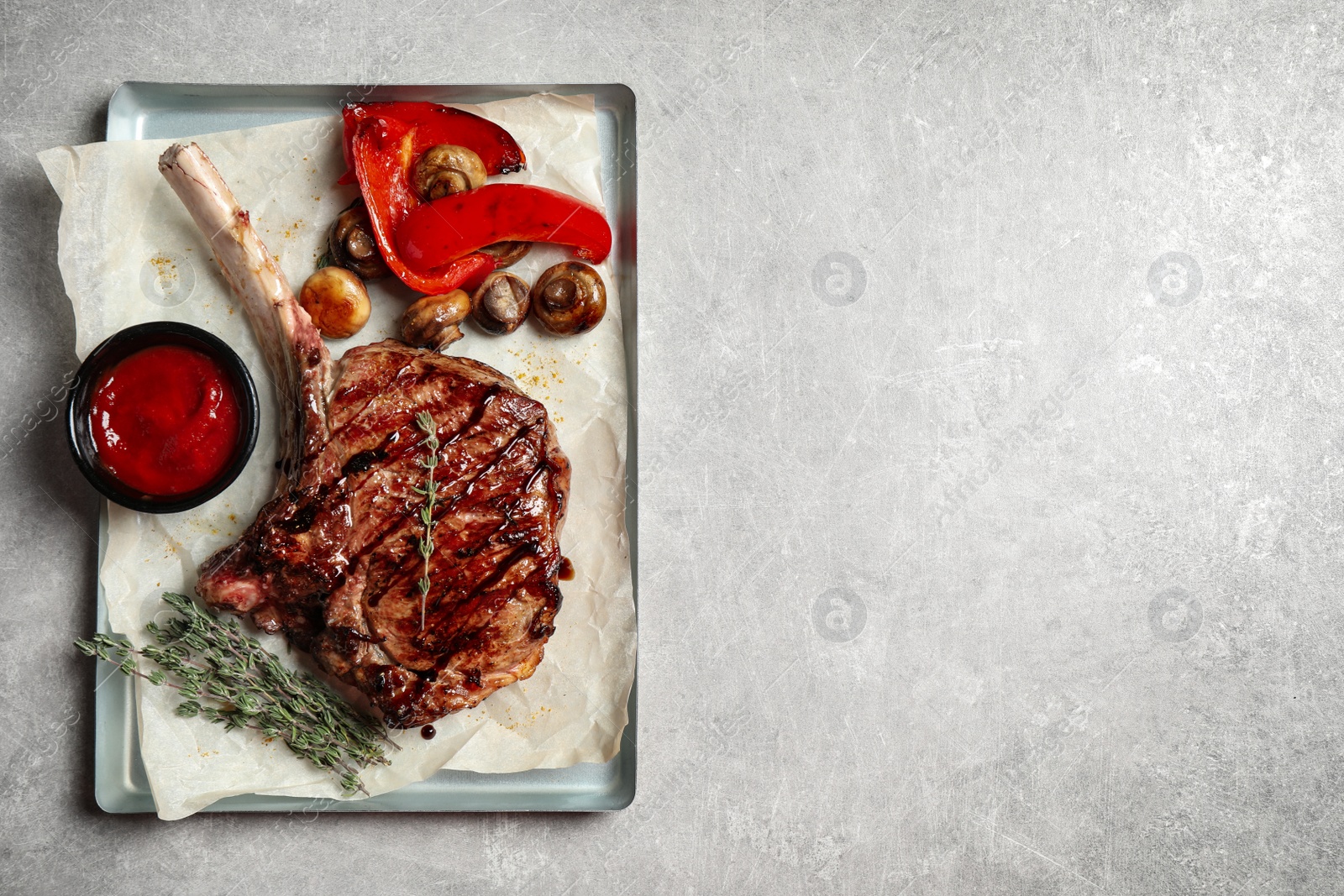 Photo of Delicious grilled ribeye with garnish on light table, top view. Space for text