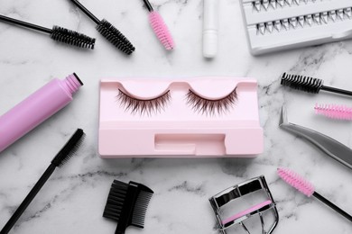 Photo of Flat lay composition with false eyelashes and tools on white marble table