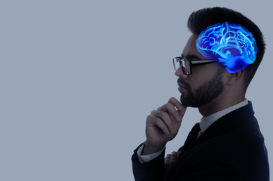 Image of Thinking concept, space for text. Young man and illustrated brain on grey background