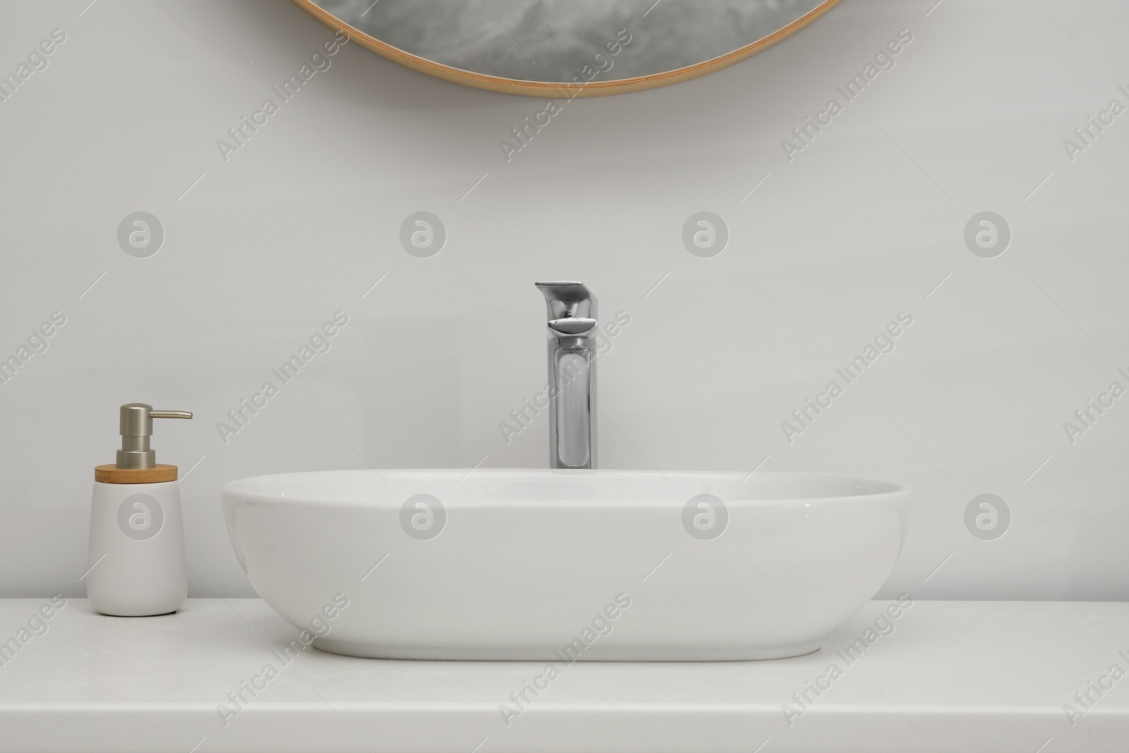 Photo of White washbasin and soap dispenser in bathroom. Interior design