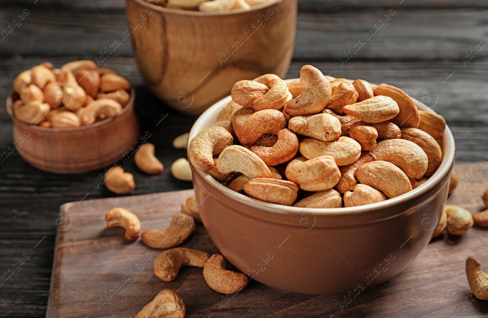 Photo of Bowl with cashew nuts on wooden table. Space for text