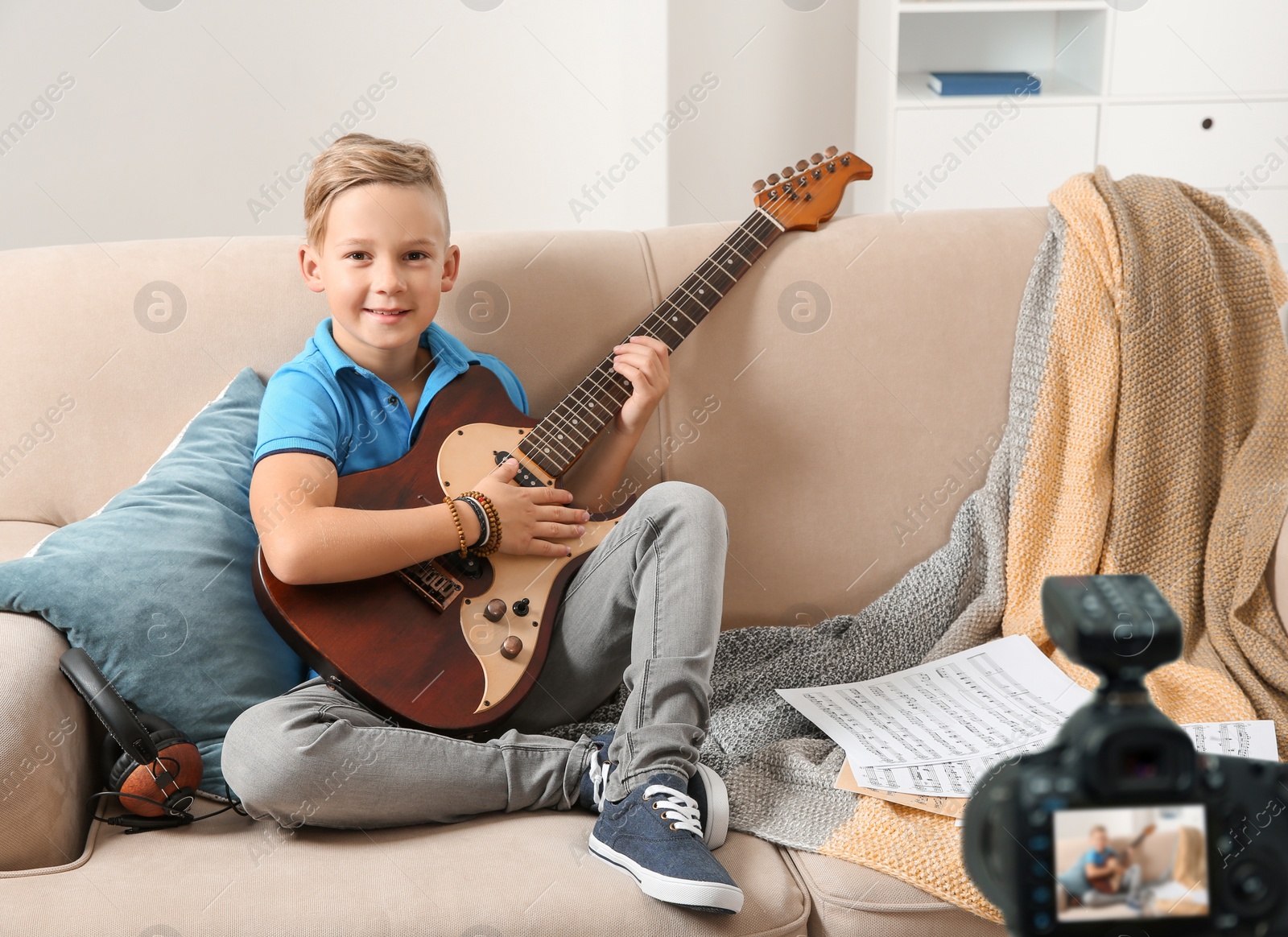 Image of Little music teacher recording guitar lesson indoors