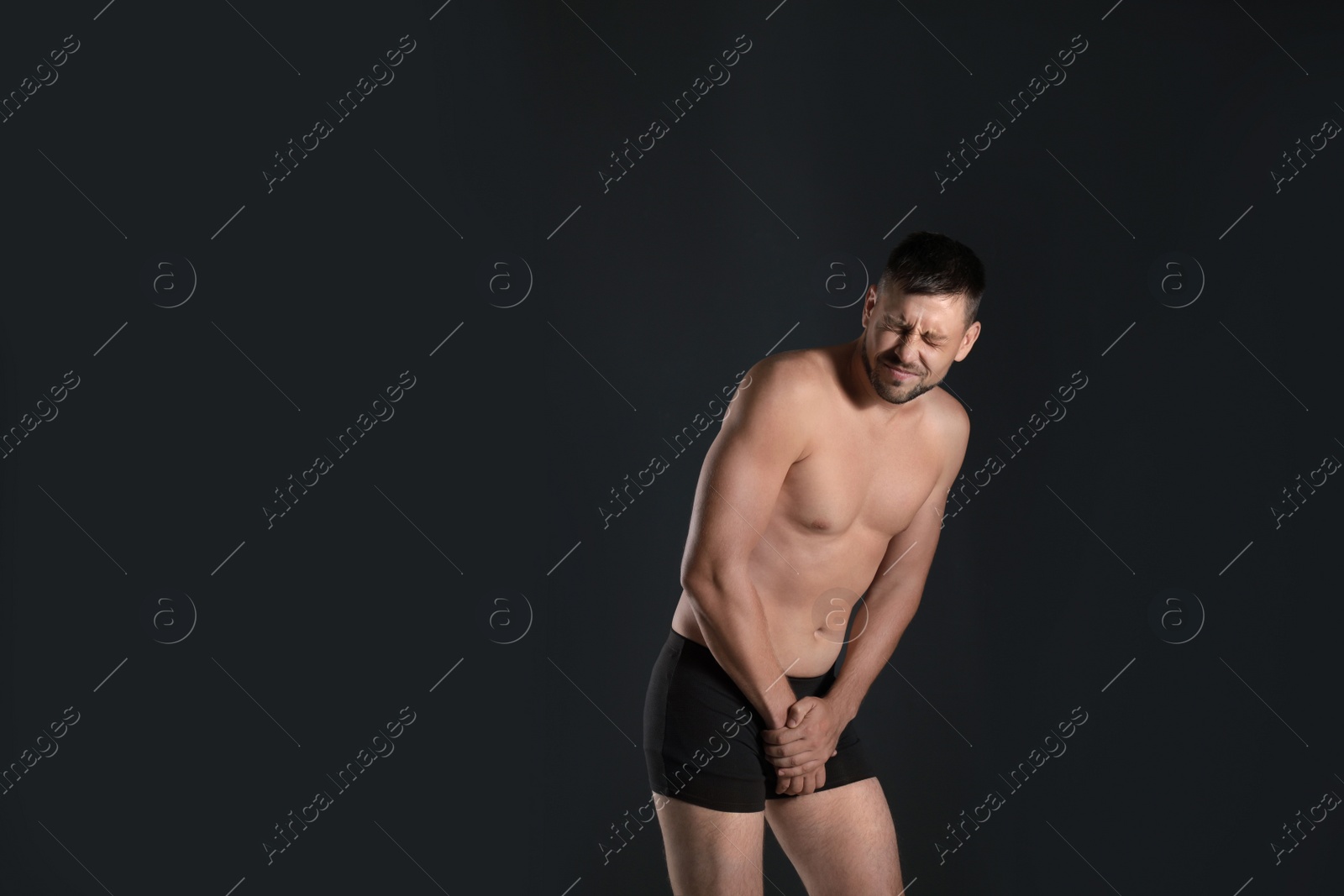 Photo of Man suffering from pain on black background, space for text. Urology problems