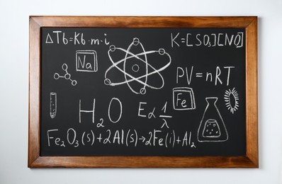 Photo of Blackboard with different chemical formulas written with chalk on white wall