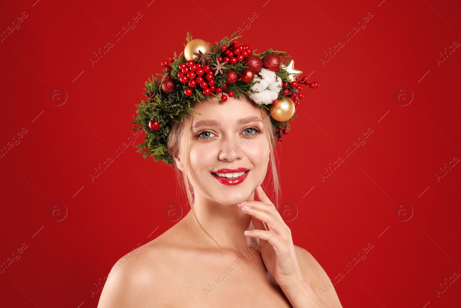 Photo of Beautiful young woman wearing Christmas wreath on red background