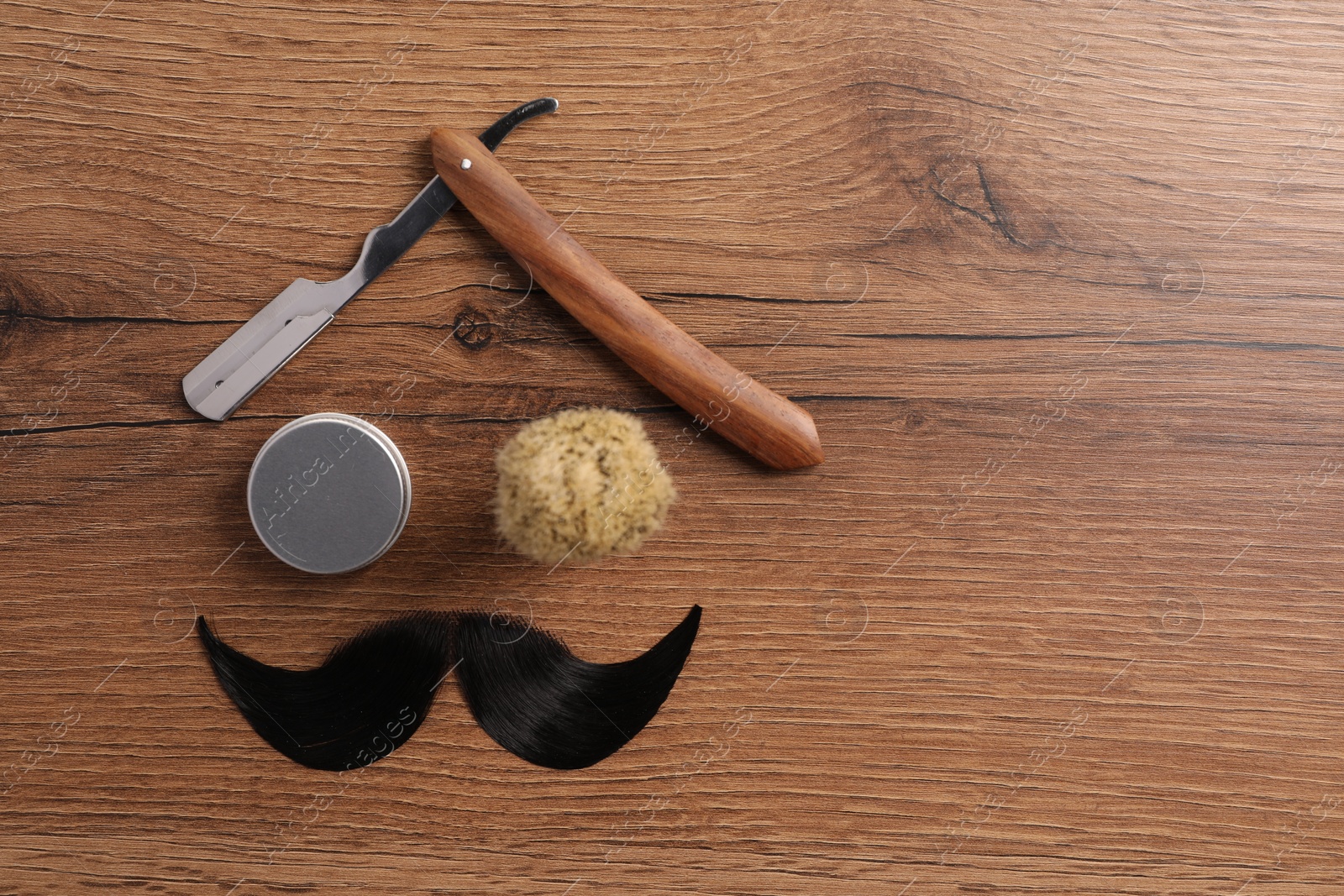 Photo of Artificial moustache and barber tools on wooden table, flat lay. Space for text