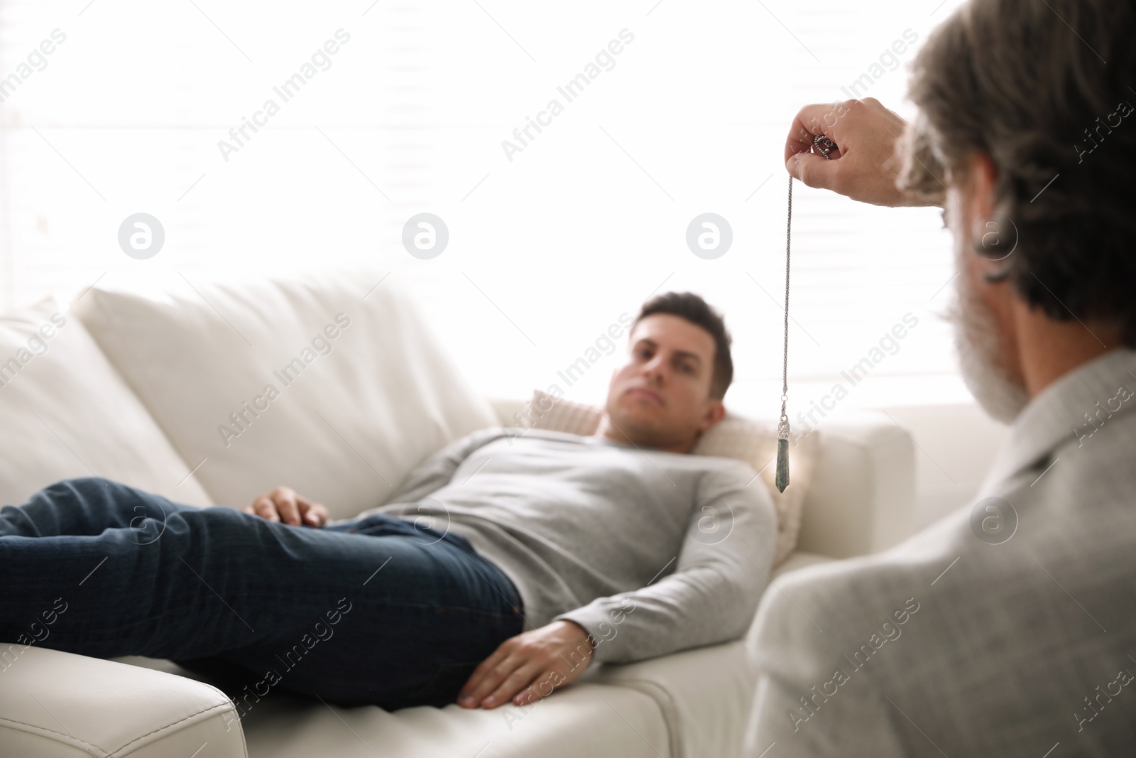 Photo of Psychotherapist using pendulum during hypnotherapy   session in office