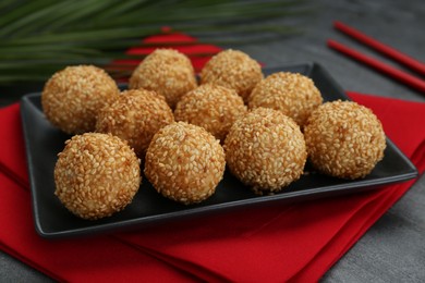 Photo of Many delicious sesame balls on black table, closeup