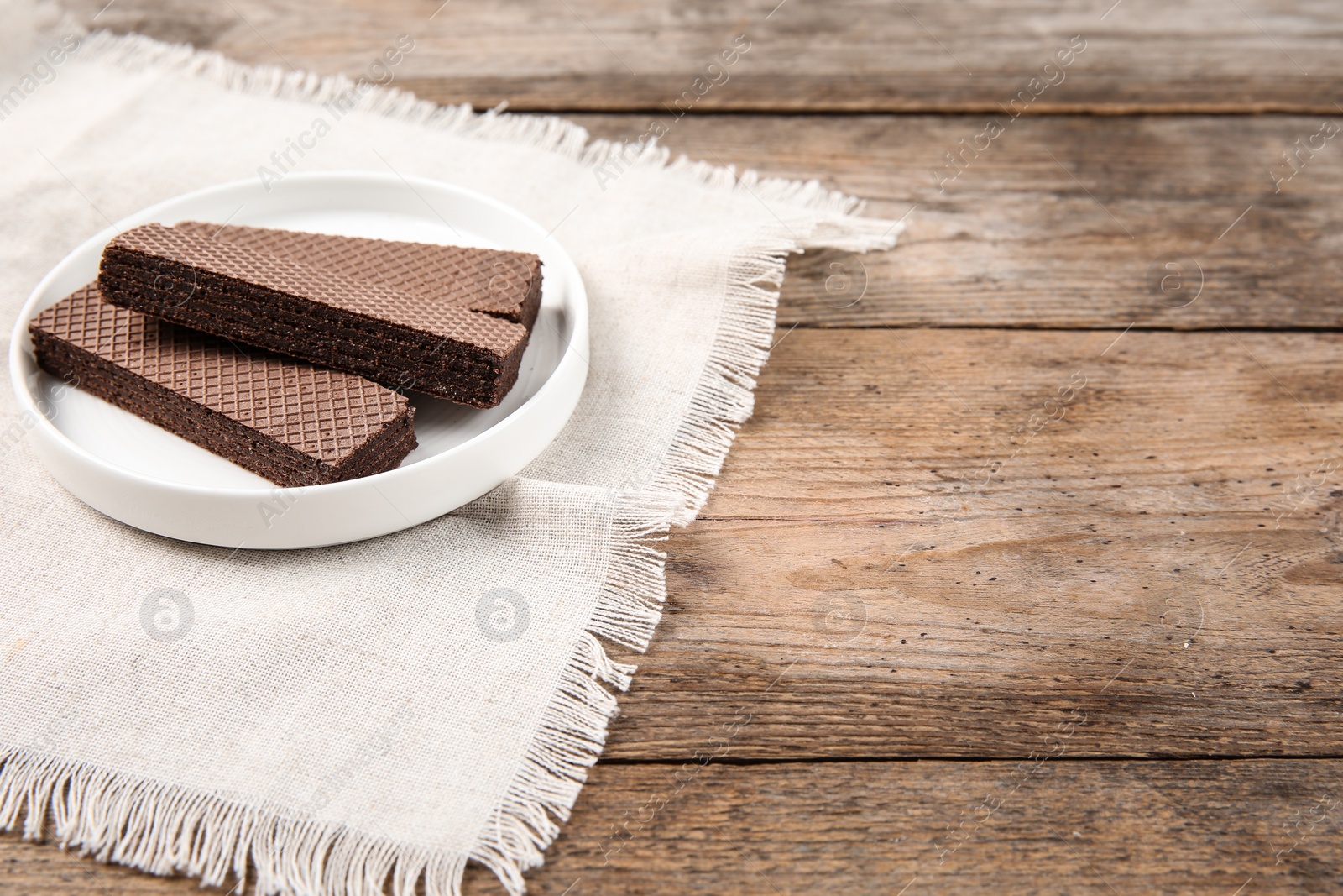 Photo of Plate of delicious chocolate wafers on brown wooden background. Space for text