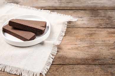 Photo of Plate of delicious chocolate wafers on brown wooden background. Space for text