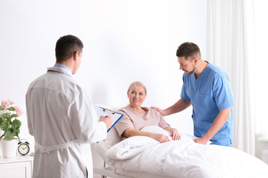 Photo of Doctor and male nurse visiting patient in hospital ward