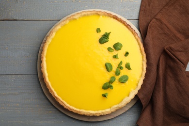 Delicious homemade lemon pie with mint on grey wooden table, flat lay