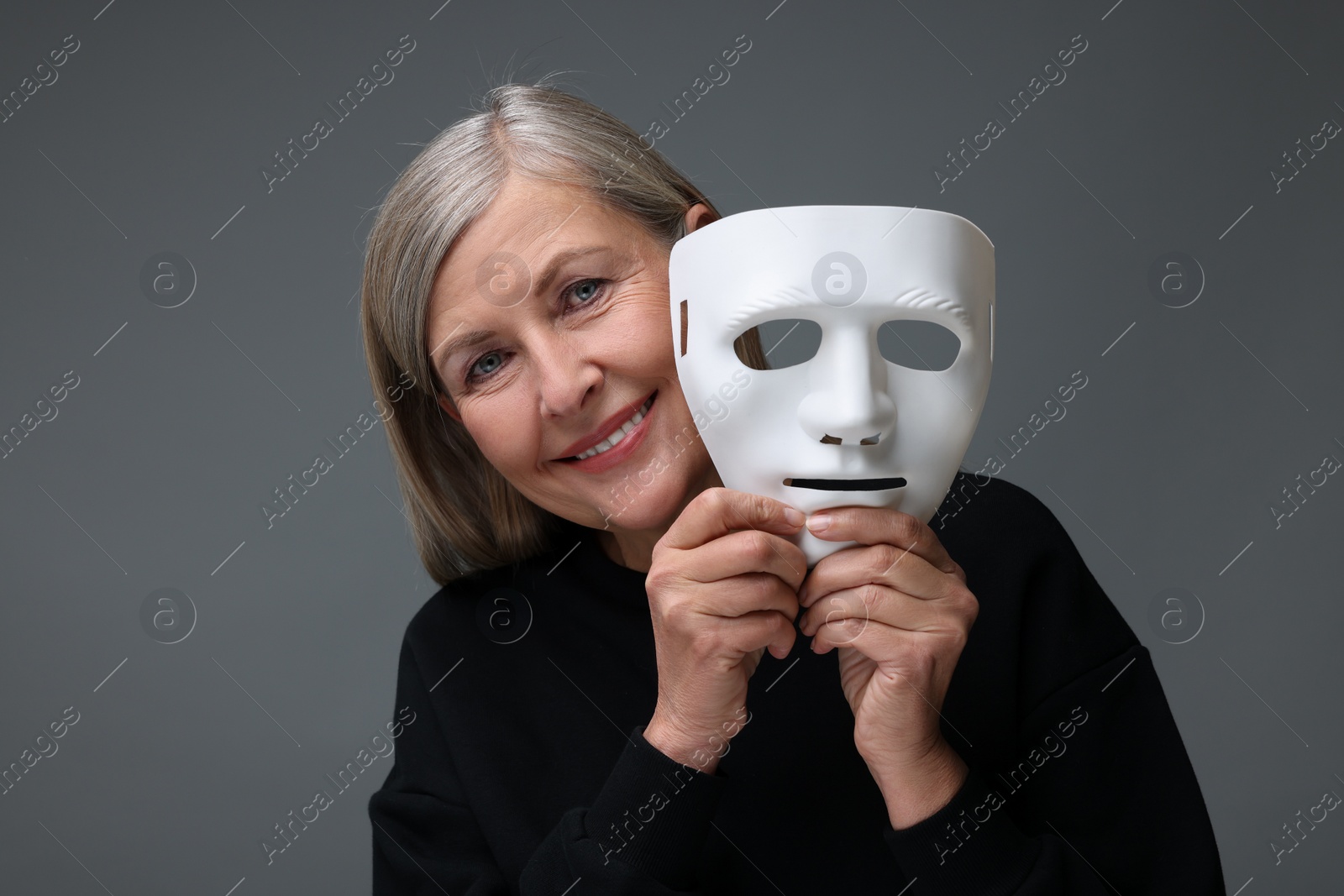 Photo of Multiple personality concept. Woman with mask on gray background