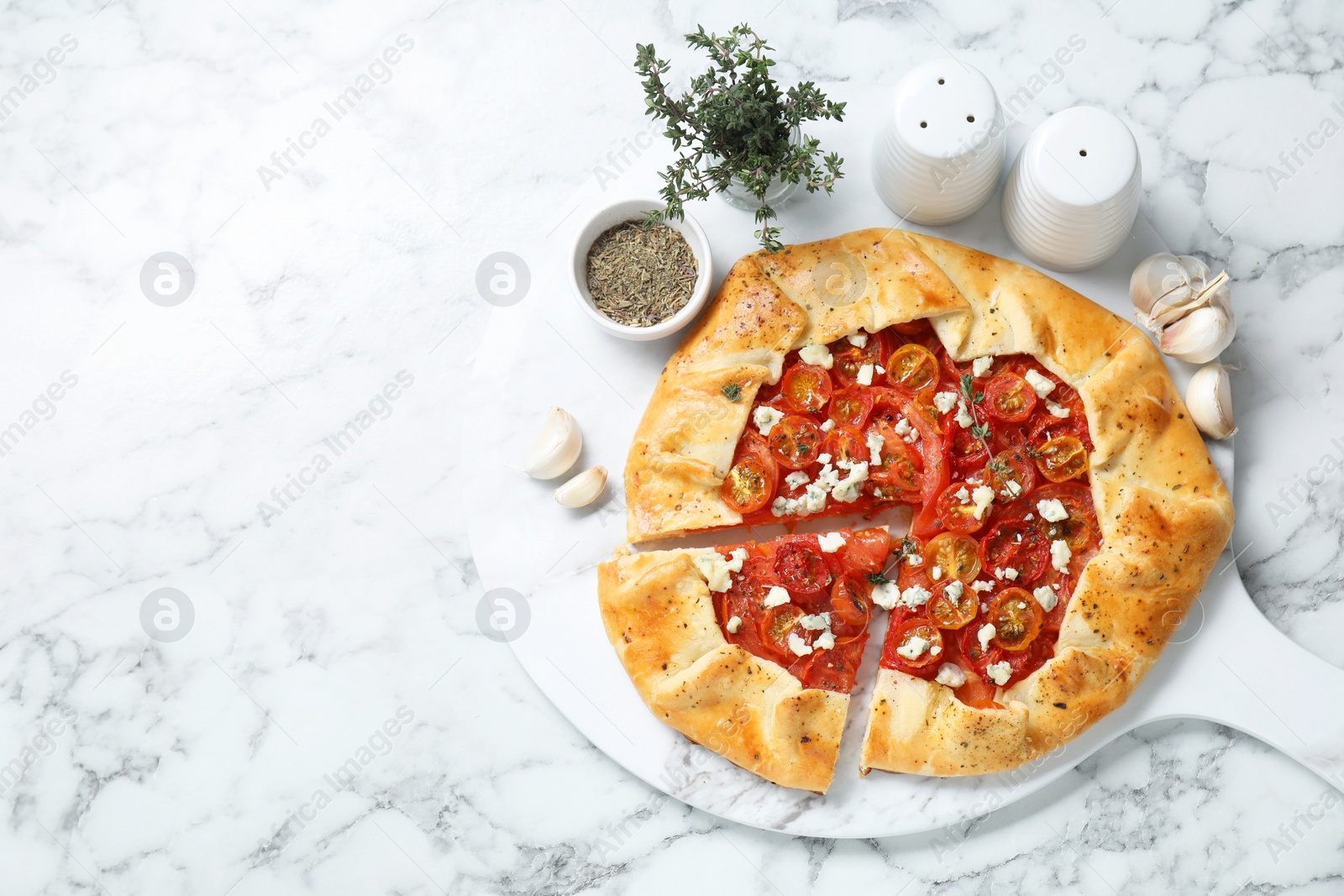 Photo of Tasty galette with tomato, thyme and cheese (Caprese galette) served on white marble table, top view. Space for text