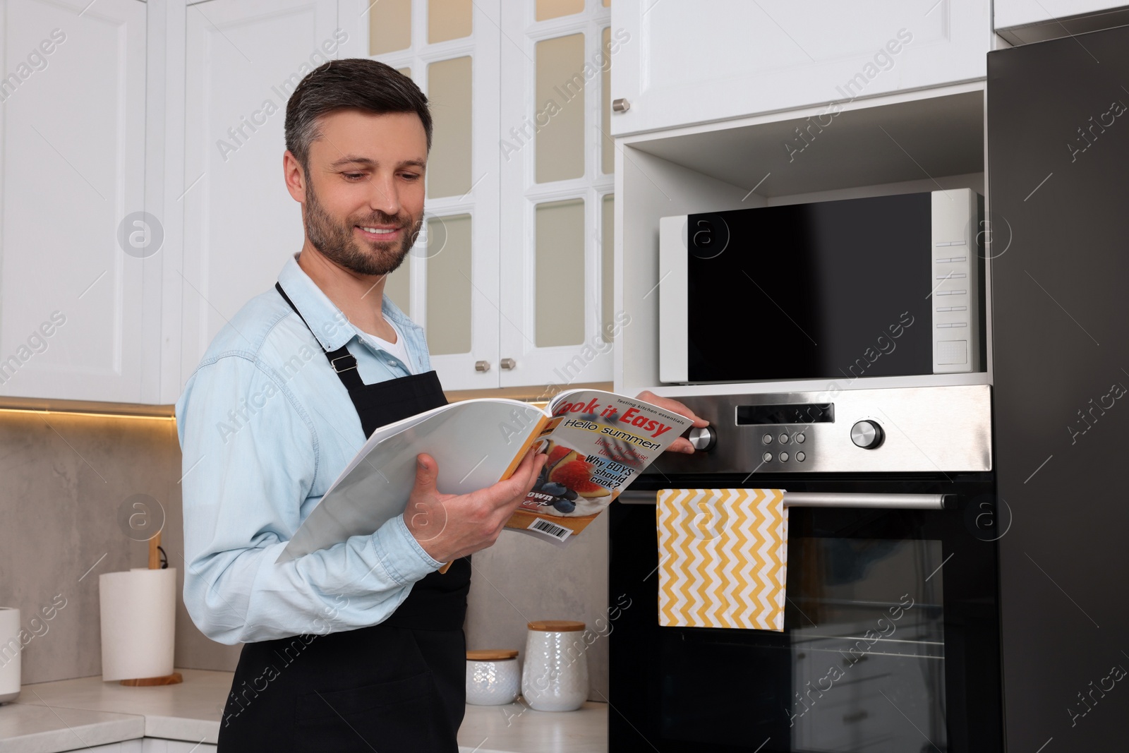 Photo of Adult man reading food magazine in kitchen