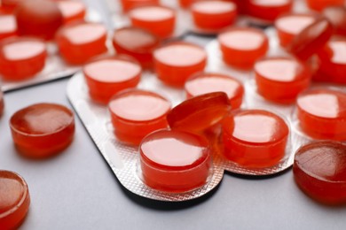 Orange cough drops on grey background, closeup