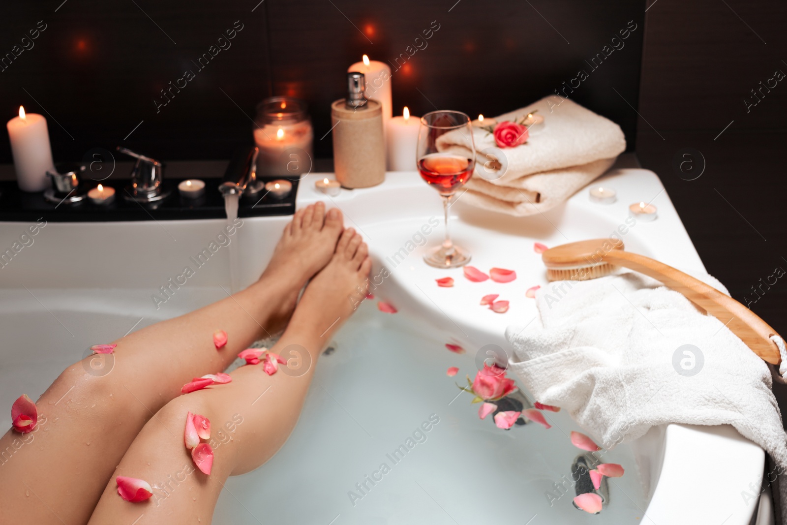 Photo of Woman taking bath with rose petals, closeup. Romantic atmosphere