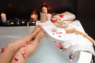 Photo of Woman taking bath with rose petals, closeup. Romantic atmosphere