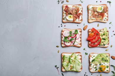 Different delicious sandwiches with microgreens on grey table, flat lay. Space for text