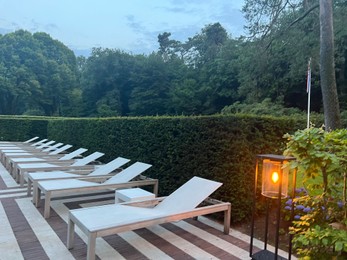 Photo of Many empty sunbeds near outdoor swimming pool at resort