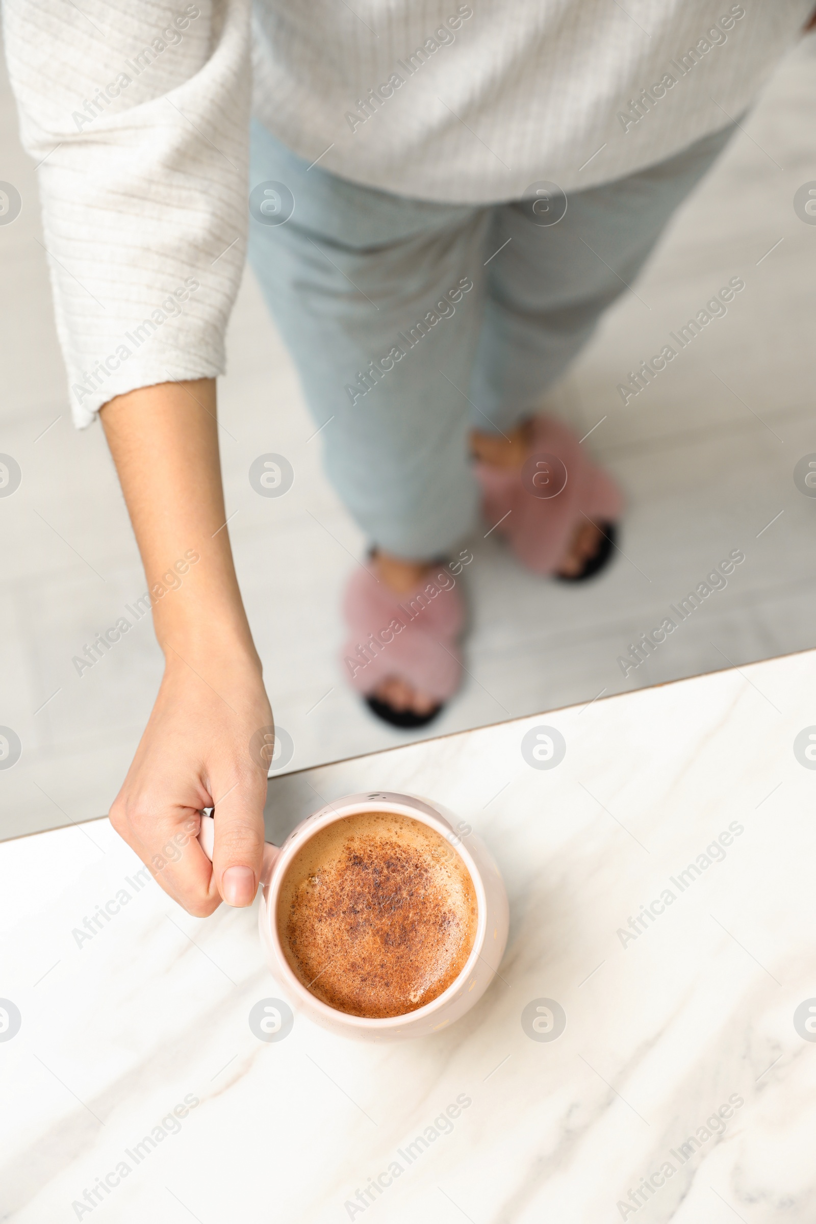 Photo of Woman holding cup of coffee at white table, top view