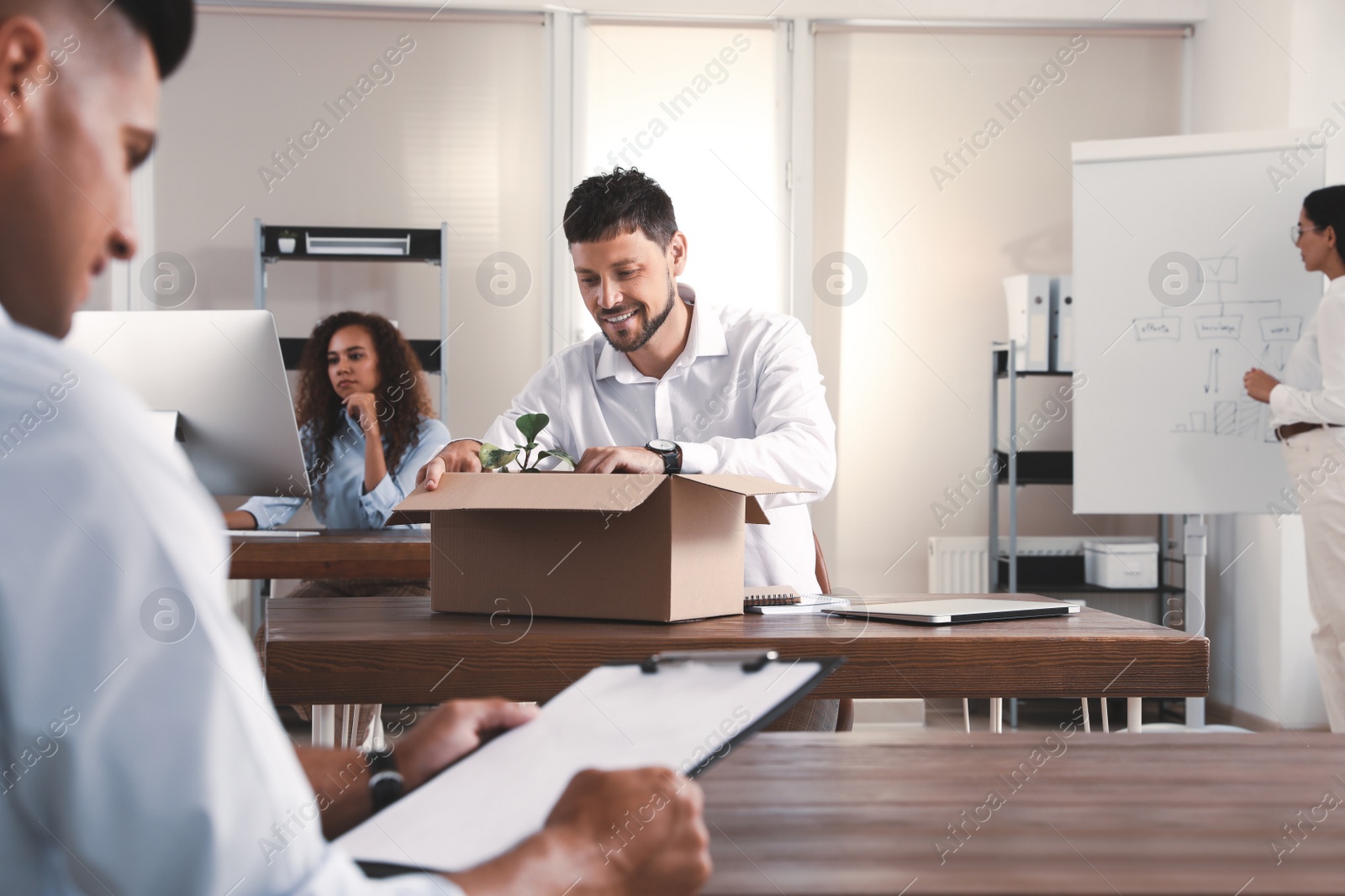 Photo of New coworker unpacking box with personal items at workplace in office