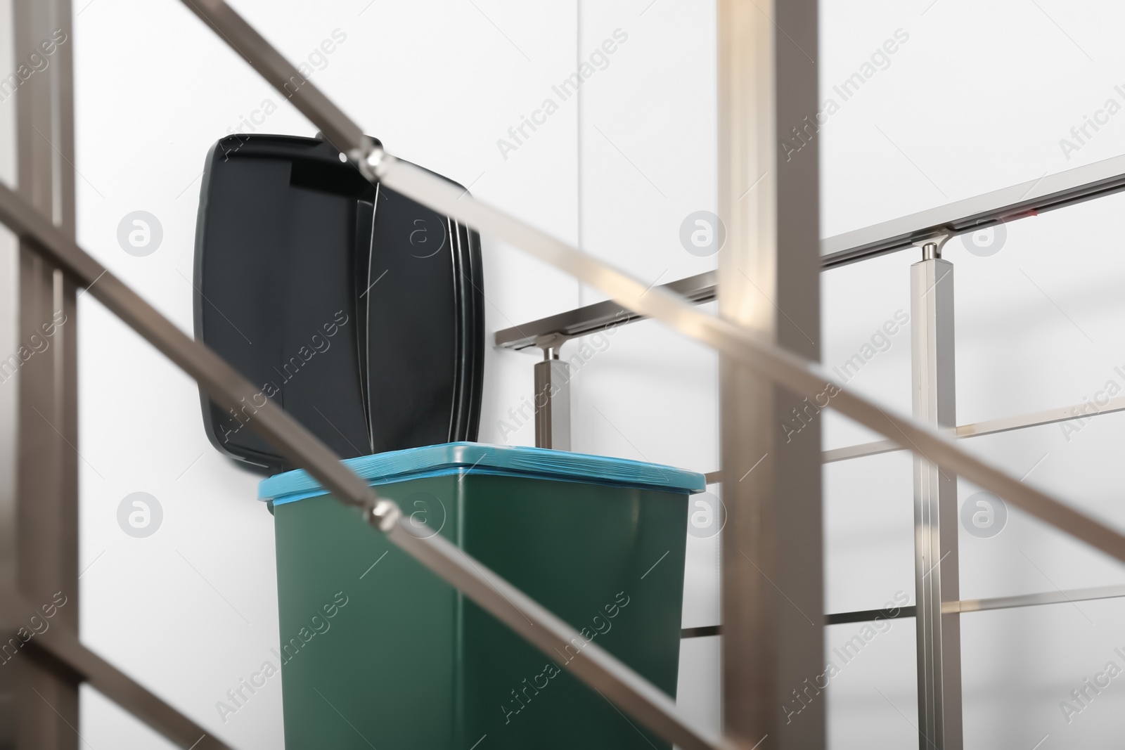 Photo of Trash bin on stair landing indoors. Waste recycling