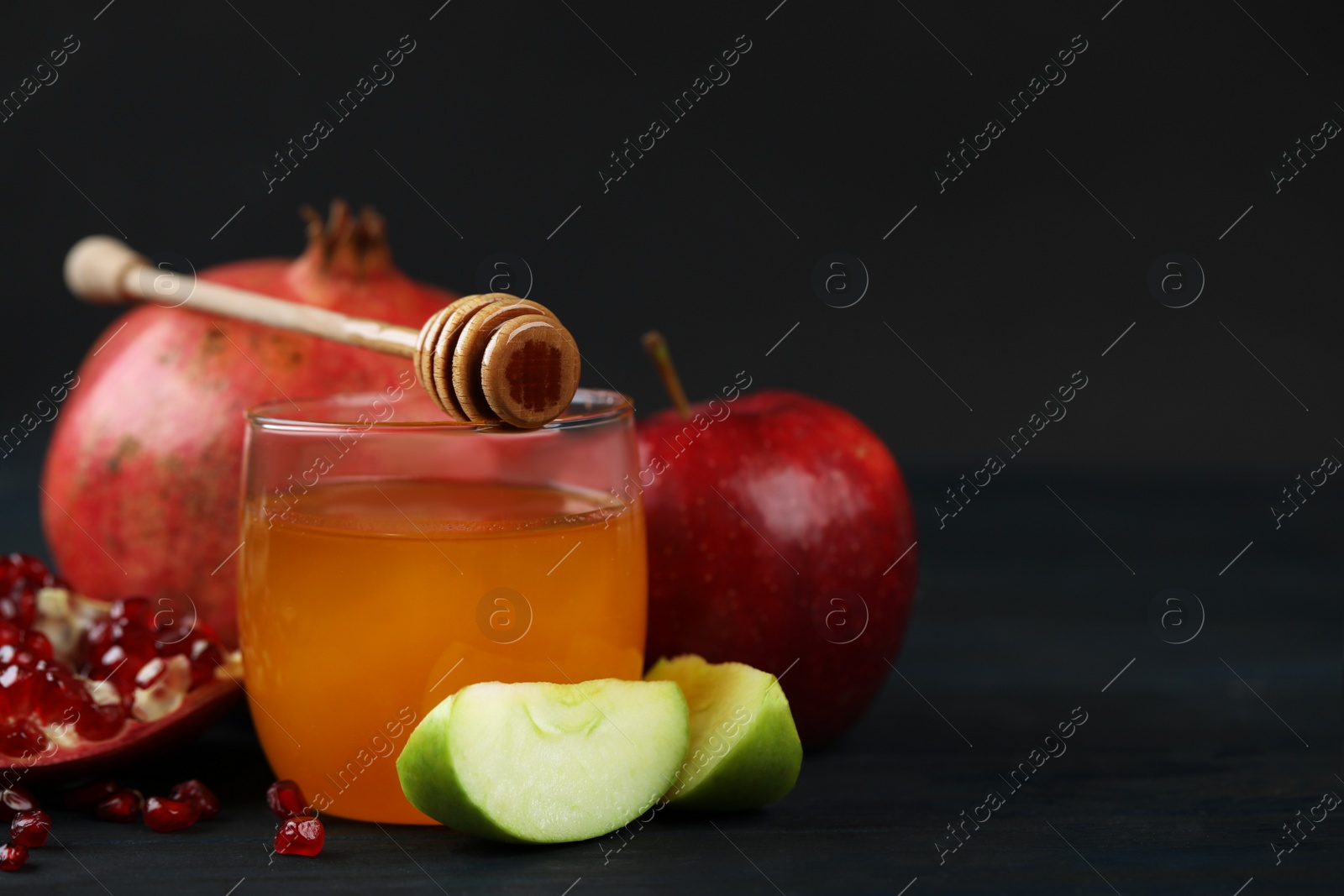 Photo of Honey, apples and pomegranate on dark wooden table, closeup. Rosh Hashanah holiday