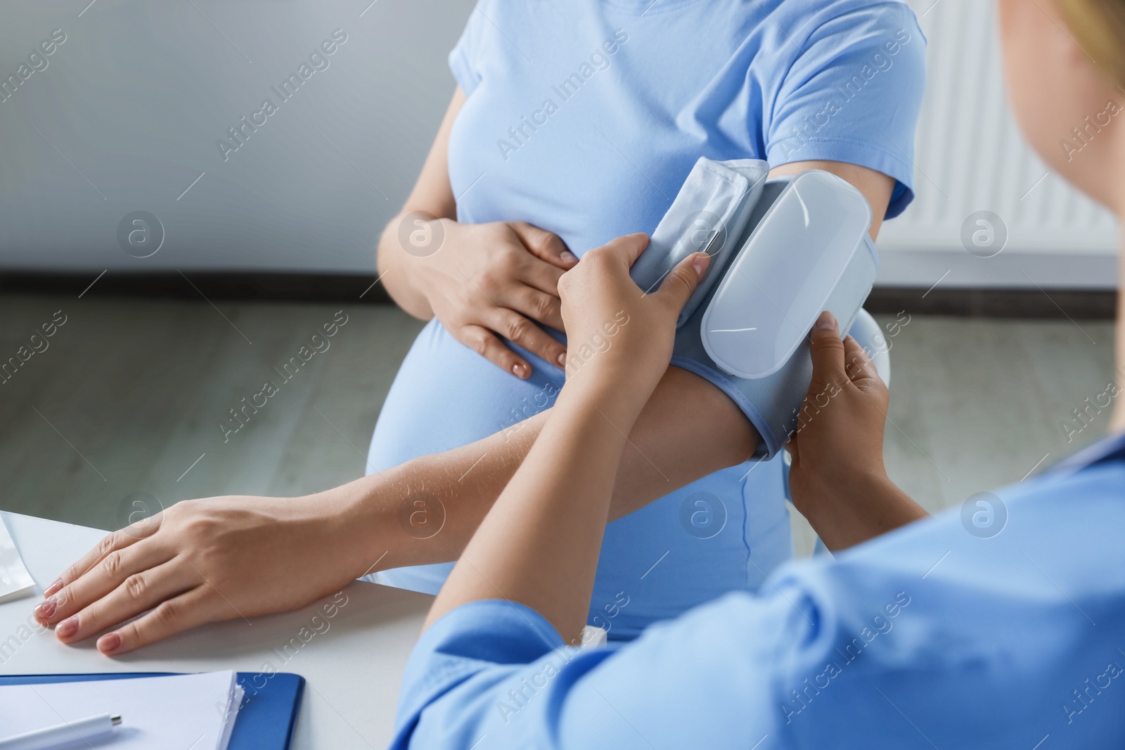 Photo of Doctor measuring blood pressure of pregnant woman in hospital, closeup