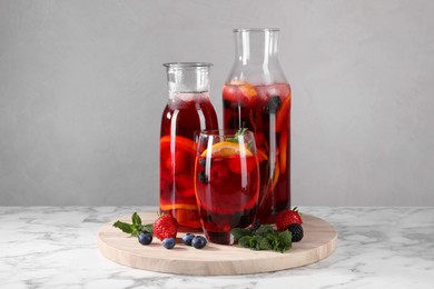 Photo of Delicious refreshing sangria and berries on white marble table