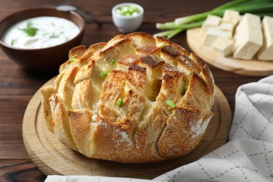 Freshly baked bread with tofu cheese, green onions and sauce on wooden table