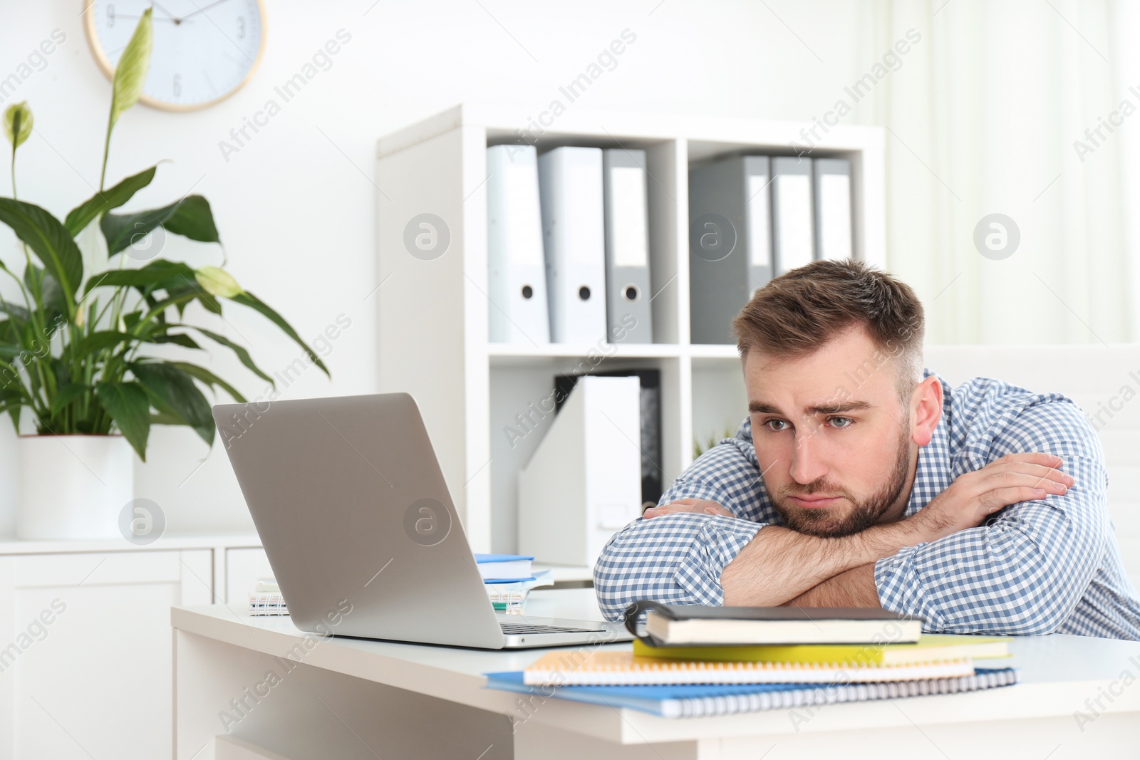 Photo of Lazy young man wasting time at table in office