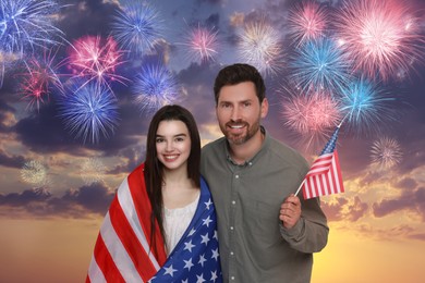 4th of July - Independence day of America. Happy father and his daughter with national flags of United States against sky with fireworks