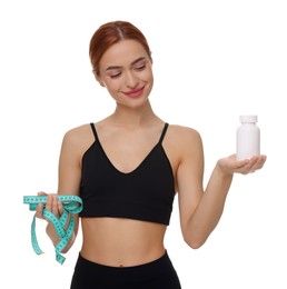 Happy young woman with bottle of pills and measuring tape on white background. Weight loss