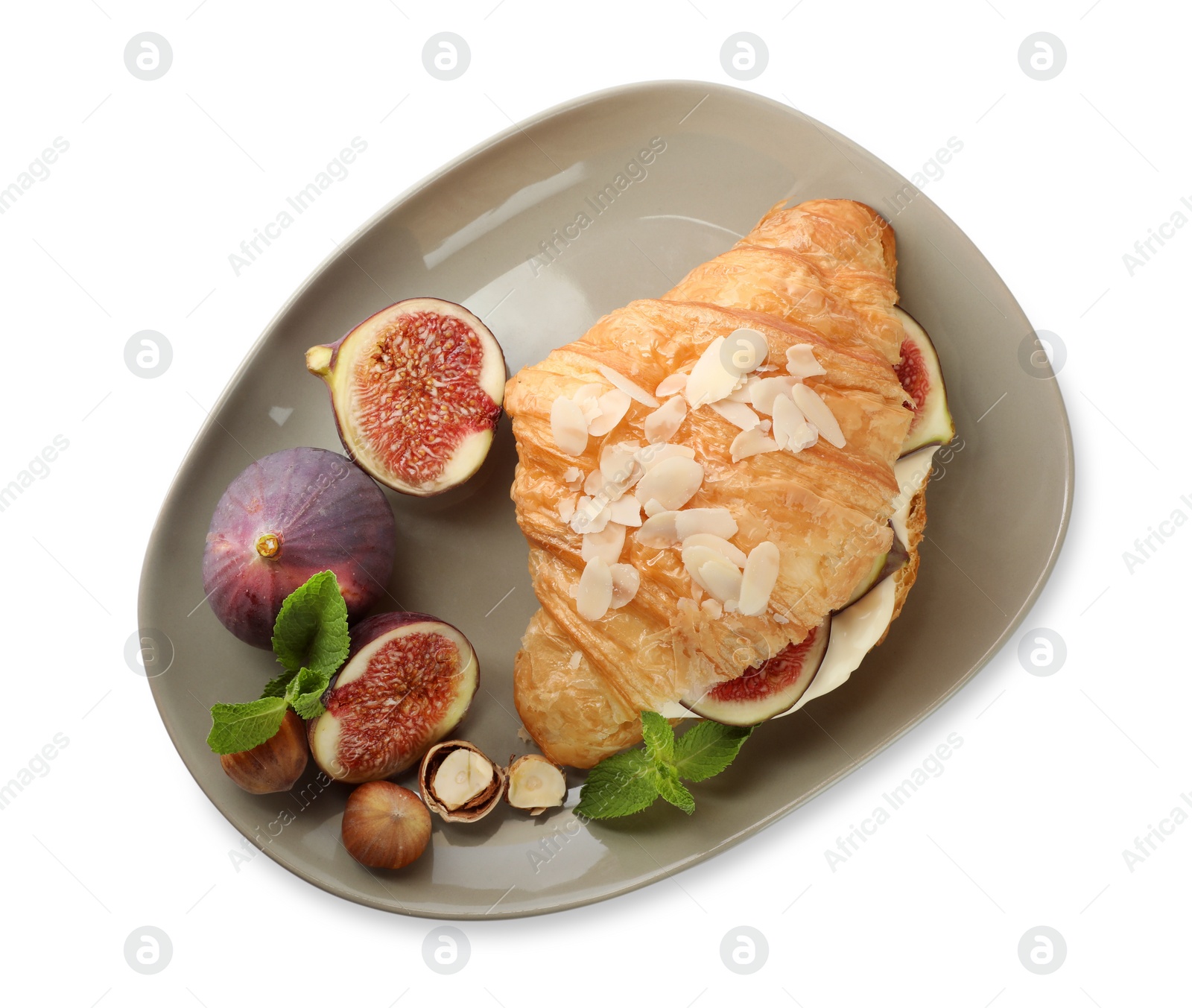 Photo of Delicious croissant with cream cheese, figs and hazelnuts isolated on white, top view