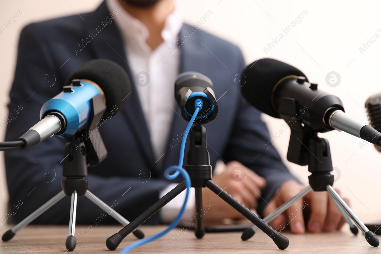 Photo of Businessman giving interview at table with microphones, closeup. Journalist conference
