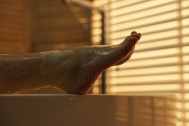 Photo of Woman taking bath with foam in tub indoors, closeup